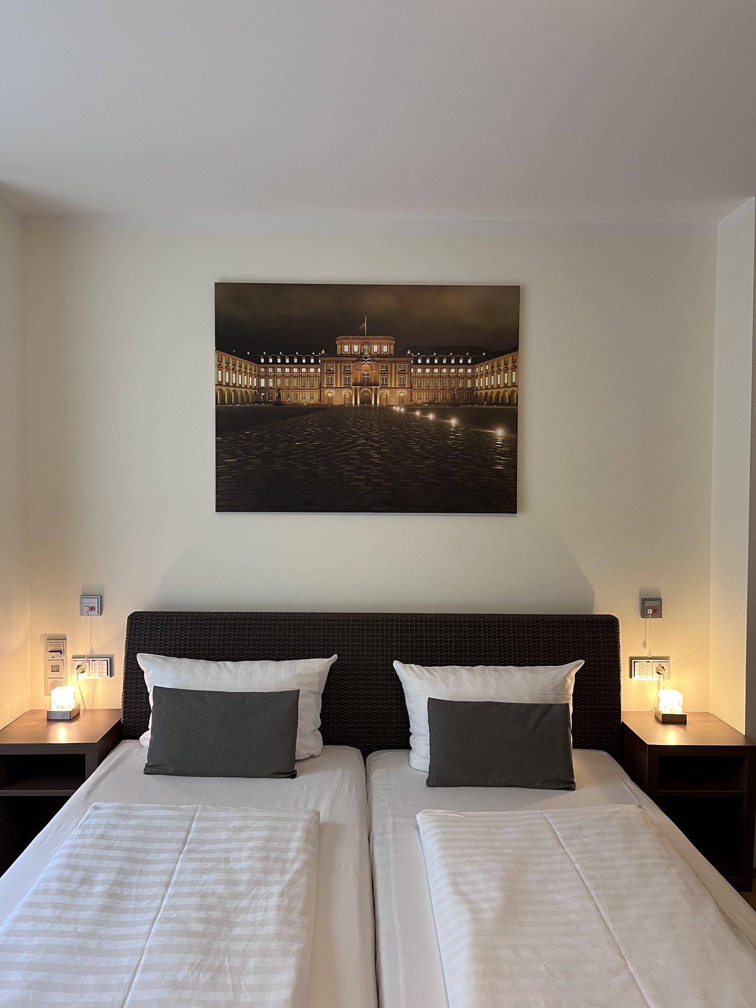 Doppelbett mit Nachttischleuchten und Bild des Mannheimer Schlosses