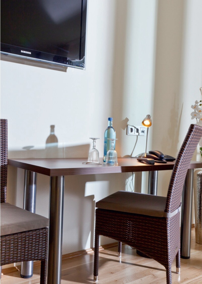 Schreibtischbereich mit Stuhl, Lampe und TV an der Wand